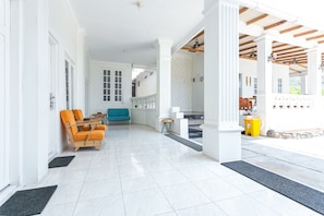A spacious indoor area with a tiled floor, wooden chairs, a blue sofa, and a small table. - RedDoorz near Grojogan Sewu Tawangmangu (Tawangmangu)