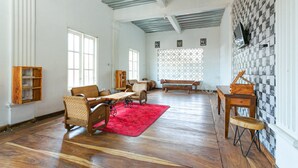 A spacious room with wooden flooring, a red rug, and a piano. - RedDoorz near Grojogan Sewu Tawangmangu (Tawangmangu)