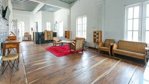 A spacious living room with wooden flooring, a red rug, and a variety of seating including a sofa and chairs. - RedDoorz near Grojogan Sewu Tawangmangu (Tawangmangu)