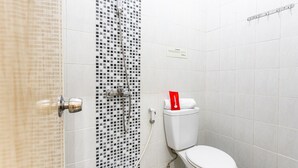Ein Badezimmer mit Toilette, Dusche und Fliesen.