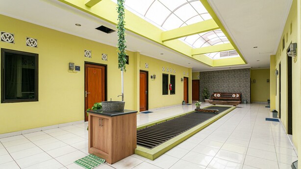 Eine großzügige Lobby mit Oberlichter, einem zentralen Pflanzenbeet und einer Rezeption.