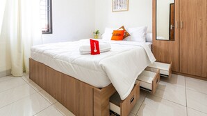 Ein modernes Schlafzimmer mit einem hölzernen Bettgestell, weißer Bettwäsche, einem roten Handtuch und einer kleinen Pflanze auf dem Nachttisch.