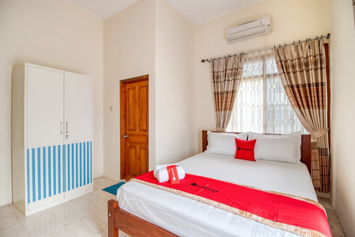 A bedroom with a bed, a wardrobe, a door, and a window with curtains.