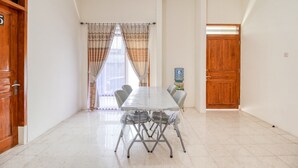 Una habitación amplia con una gran mesa de comedor, dos puertas y un ventanal con cortinas.
