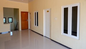 A hallway with a polished floor, a wooden door labeled 124, and a window with a shutter.