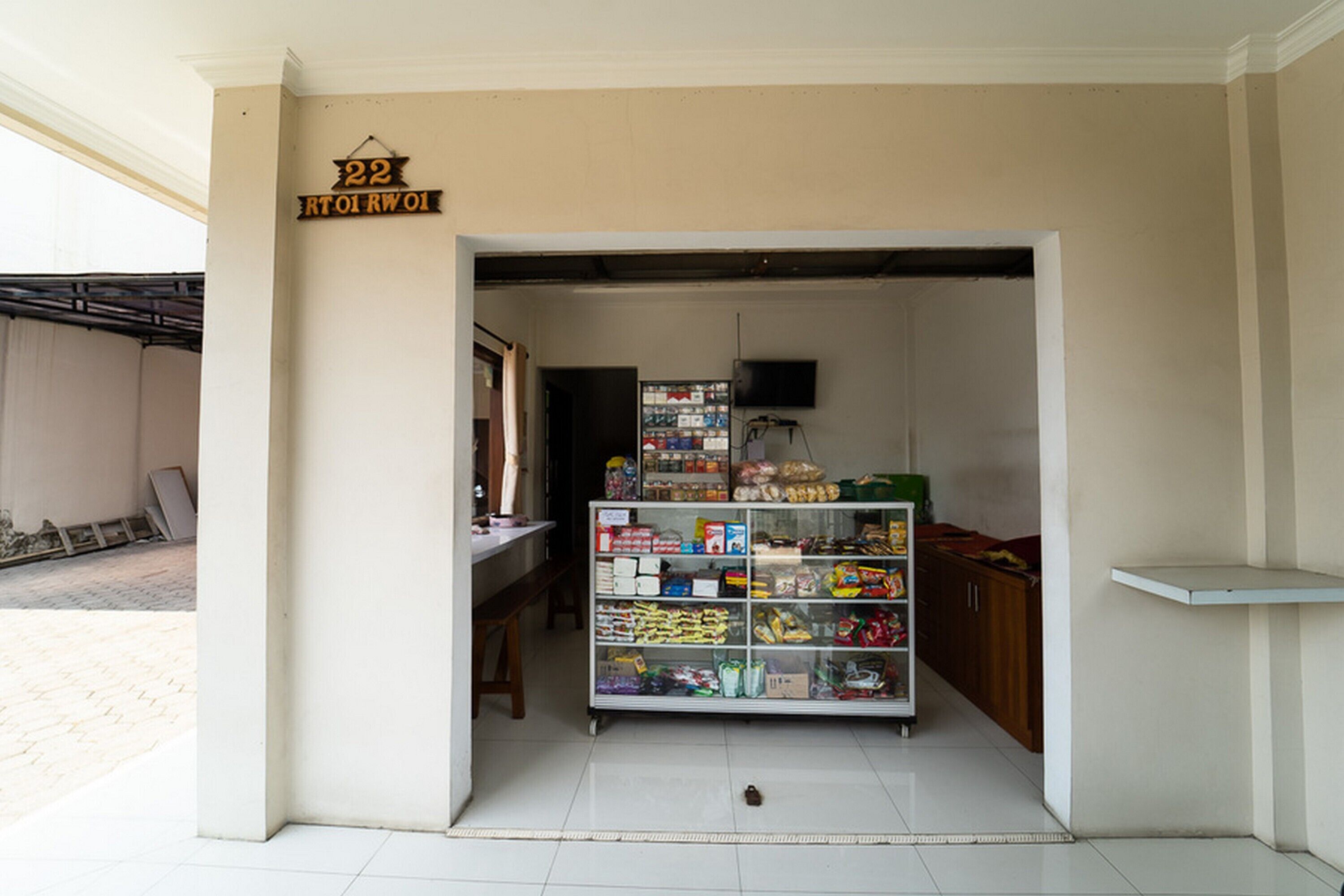 A small grocery store with a tiled floor and a variety of packaged goods on shelves.