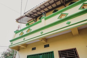 A building with a yellow facade, green trim, and multiple windows. - RedDoorz Syariah near Stadion Maulana Yusuf (Serang)