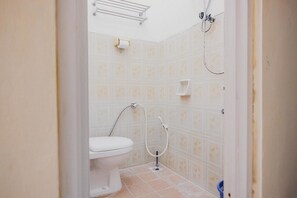 A bathroom with a toilet, shower, and a towel rack.