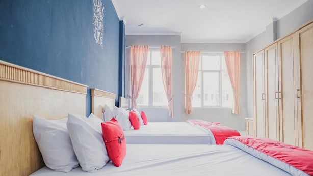A hotel room with two beds, each with white and red bedding, a wooden headboard, and a large window with curtains. - RedDoorz @ Jalan Hayam Wuruk Lampung 2 (Bandar Lampung)