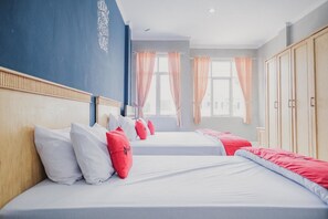 Una habitación de hotel con dos camas, cada una con ropa de cama blanca y roja, un cabecero de madera y un ventanal con cortinas.