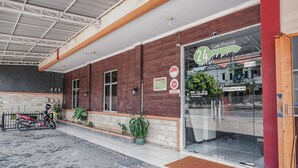 A guesthouse with a brick facade, a motorcycle parked outside, and a glass entrance. - RedDoorz @ Jalan Hayam Wuruk Lampung 2 (Bandar Lampung)