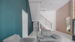A modern living room with two grey sofas, a wooden coffee table, and a staircase leading to an upper floor. - RedDoorz @ Jalan Hayam Wuruk Lampung 2 (Bandar Lampung)