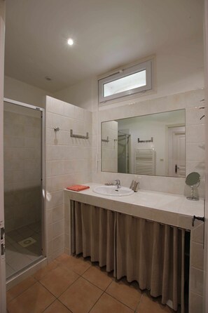 Une salle de bain équipée d’une douche, d’un lavabo, d’un miroir et d’un porte-serviettes.