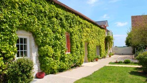 A building with ivy-covered walls, a visible window, and a pathway leading to a gate.