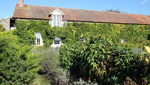 A large house with a brick chimney, ivy-covered walls, and multiple windows.