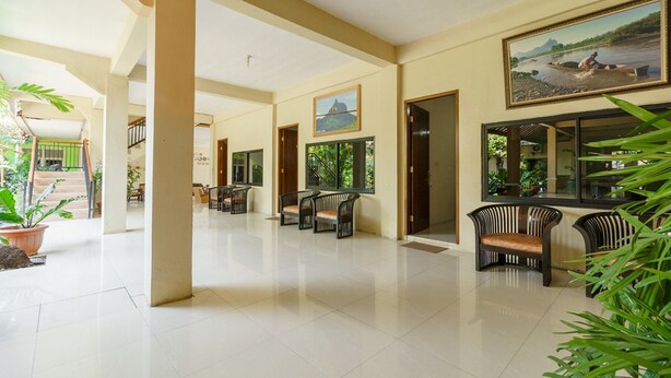 A spacious lobby with a tiled floor, several chairs, and potted plants.