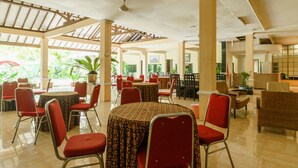 A spacious indoor area with multiple tables and chairs, a ceiling fan, and potted plants.