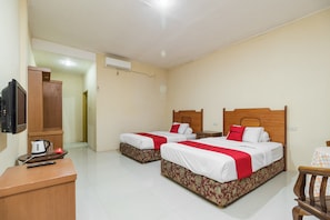 A hotel room with two beds, a TV, a desk, and a chair.