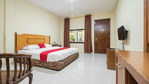 A hotel room with a wooden bed, a desk, a chair, and a television.