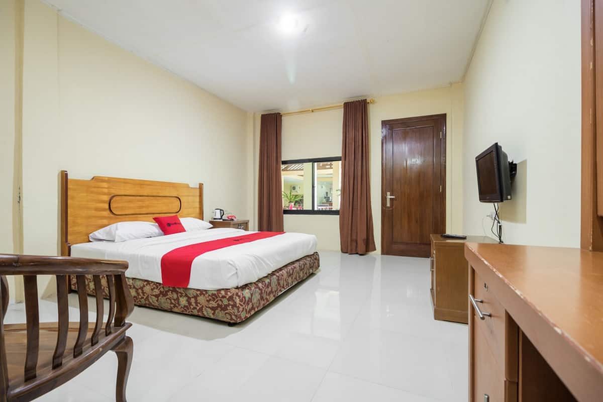 Een hotelkamer met een houten bed, een bureau, een stoel en een televisie.