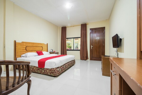 A hotel room with a wooden bed, a desk, a chair, and a television.