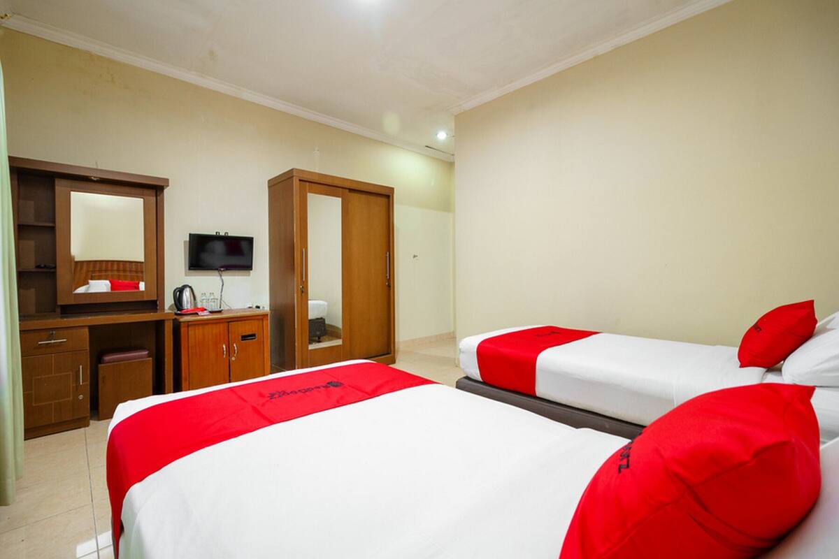 Hotelkamer met twee bedden, een televisie, een kledingkast en een bureau met spiegel.