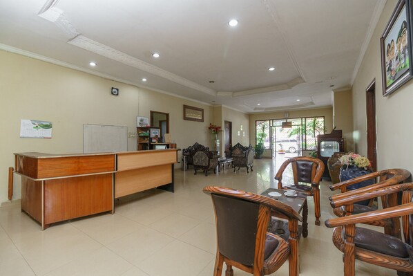 A reception area with a wooden desk, several chairs, a whiteboard, and framed pictures on the walls.