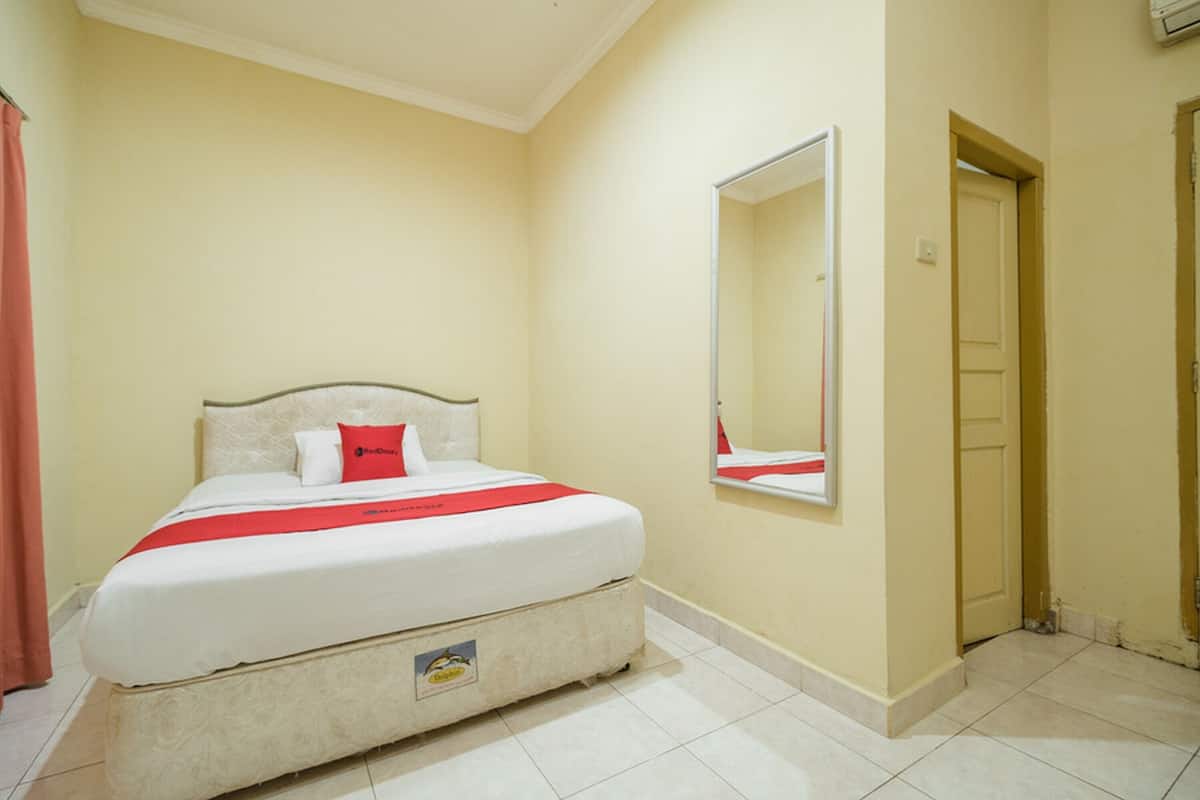 Een slaapkamer met een bed, een spiegel en een deur.