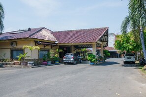 A two-story building with a tiled roof, a covered porch, and a car parked in front.