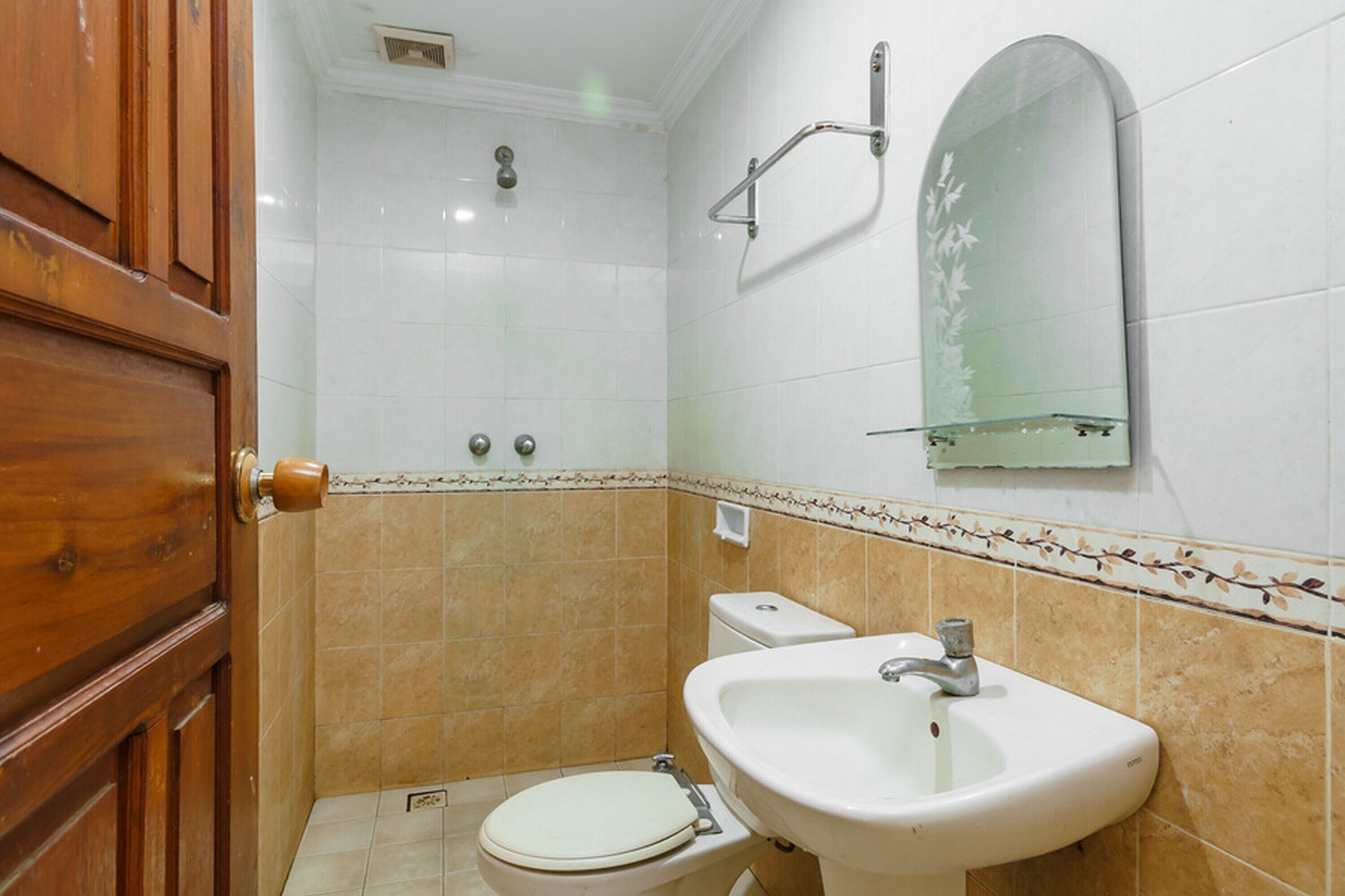 Et badeværelse med toilet, håndvask og brusebad.