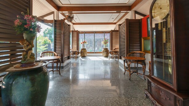A spacious lobby with wooden shutters, a large clock, and a vase with flowers. - RedDoorz near Transmart Pangkal Pinang (Pangkalpinang)