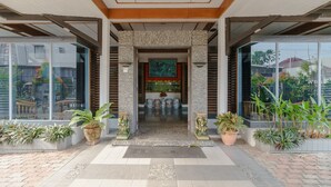 A hotel entrance with a tiled floor, potted plants, and a central doorway framed by stone pillars. - RedDoorz near Transmart Pangkal Pinang (Pangkalpinang)