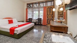 A hotel room with a bed, a desk, a chair, a television, and a window with curtains. - RedDoorz near Transmart Pangkal Pinang (Pangkalpinang)