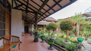A covered patio with wooden benches and potted plants. - RedDoorz near Transmart Pangkal Pinang (Pangkalpinang)