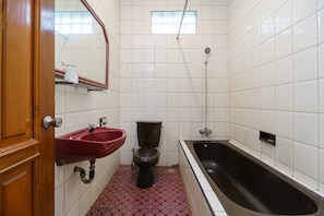 A bathroom with a wooden door, a red sink, a black toilet, and a black bathtub.