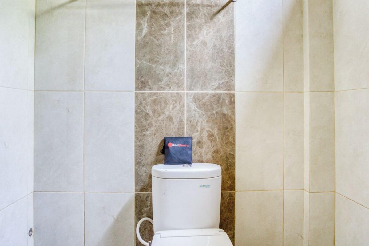 Une salle de bain avec des toilettes, un sac Red Doorz posé sur la cuvette, et un mur en marbre.