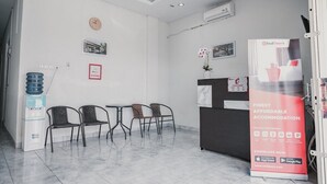 Un área de recepción con un mostrador, sillas, dispensador de agua y un anuncio de RedDoorz.