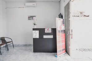 Zona de recepción con mostrador de mármol, una silla, una orquídea en maceta y un letrero de RedDoor.