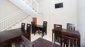 A dining area with a staircase, wooden tables, and chairs. - RedDoorz Syariah near UNTAG Banyuwangi 2 (Banyuwangi)