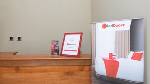 A hotel reception desk with a framed certificate, a RedDoorz poster, and a brochure. - RedDoorz Syariah near UNTAG Banyuwangi 2 (Banyuwangi)