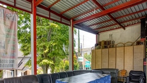 A covered outdoor seating area with a checkered table and leather sofas. - RedDoorz near Paralayang Batu (Batu)