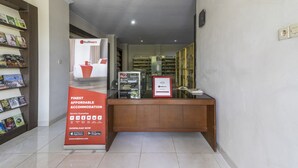 A reception desk with a RedDoorz sign, a glass display case, and a bookcase with magazines. - RedDoorz near Condongcatur Bus Station (Depok)