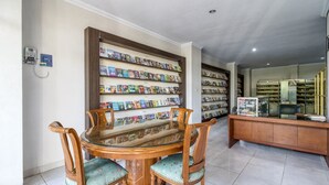 A library with a wooden table and chairs, surrounded by bookshelves filled with books. - RedDoorz near Condongcatur Bus Station (Depok)