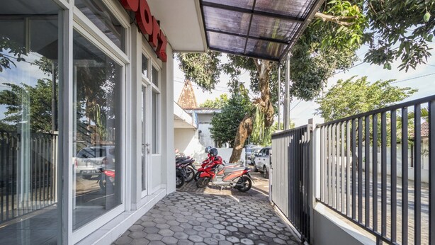 A building with large glass windows, a covered walkway, and a metal fence. - RedDoorz near Condongcatur Bus Station (Depok)
