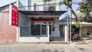 A RedDoorz building with a metal gate and a red signboard. - RedDoorz near Condongcatur Bus Station (Depok)