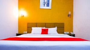 Une chambre d’hôtel comprenant un lit, une tête de lit, une table de chevet, un téléphone et une lampe fixée au mur.