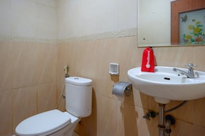 A bathroom with a toilet, sink, and a toilet paper holder.