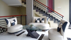 Un salon moderne avec une table basse en verre, deux canapés et un escalier doté de rampes rouges.