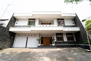 A modern two-story house with a flat roof, a central entrance, and a covered driveway. - KoolKost near Padjadjaran University (Bandung)