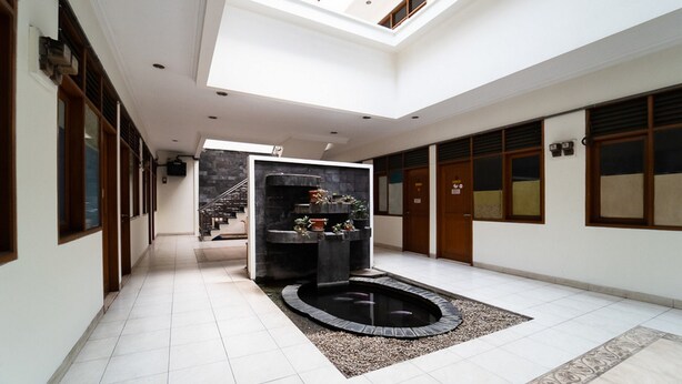 A spacious interior with a central water feature, a skylight, and a staircase leading to an upper level. - KoolKost near Padjadjaran University (Bandung)